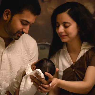 A classic family portrait with the parents gazing lovingly at their newborn. I guide families into natural poses that feel authentic and highlight their bond during these precious first days.