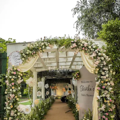 The entrance to our "Baby in Bloom" enchanted garden baby shower. A beautiful white pergola was draped in soft fabric and adorned with a lush arch of pink and white roses, setting a dreamy tone from the start.