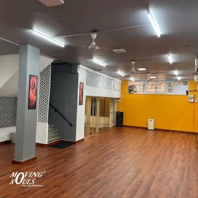A wide view of our spacious studio with its bright yellow wall and professional dance floor. This is where the magic happens.