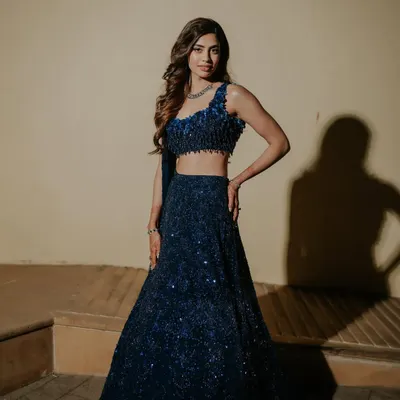 A stunning, full-length shot of the bride in her midnight blue sequined lehenga for the Sangeet. The makeup is glamorous, with a focus on the eyes, perfect for a night of dancing.