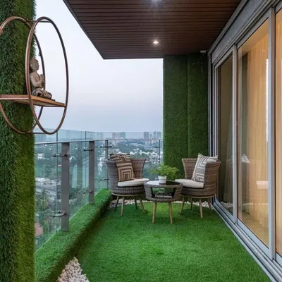 A modern high-rise balcony designed for serenity. We used artificial grass walls and flooring, a white pebble bed, and minimalist decor to create a peaceful zen corner with a stunning city view.