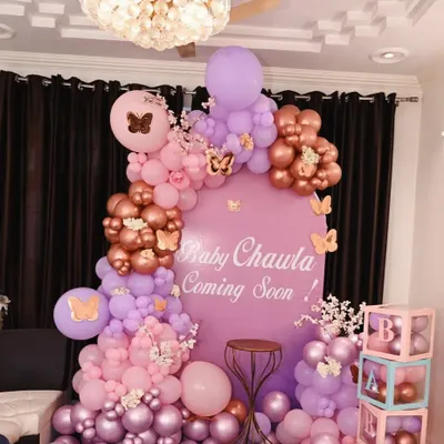 A gorgeous butterfly-themed baby shower with a custom backdrop, 'BABY' blocks, and a balloon arrangement in pink, purple, and rose gold.