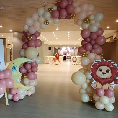 A grand entrance arch for a lion-themed party. This arch in dusty pink and cream colors, with cute moon and lion cutouts, welcomes guests into the celebration hall.