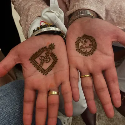 An elegant mehandi design for the groom, featuring an 'Om' symbol and a wedding hashtag. It's a perfect way for the groom to participate in the tradition.