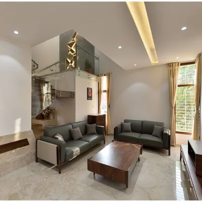 A modern living room in Mr. Ramu Siddappa's residence, where a double-height space above the staircase creates a sense of volume and connection between floors.