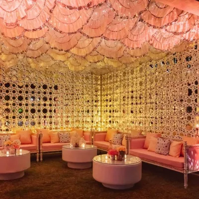A full view of the magnificent Sheesh Mahal inspired tent. The combination of intricate mirror-work walls, a scalloped ceiling, and plush pink seating creates a truly royal and immersive experience for your guests.