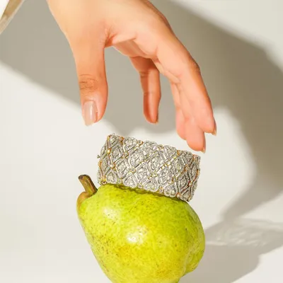 A creative and playful shot where a stunning diamond bracelet from Sarte Jewellery rests on a fresh pear. This unexpected pairing creates a memorable, artistic image that highlights the piece's unique design.