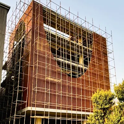 The Shang Chi Cafe and Restaurant project during the construction phase in Noida. This image captures the building's core structure and the intricate scaffolding required to install the signature curved facade, showing our ambitious design taking physical form.