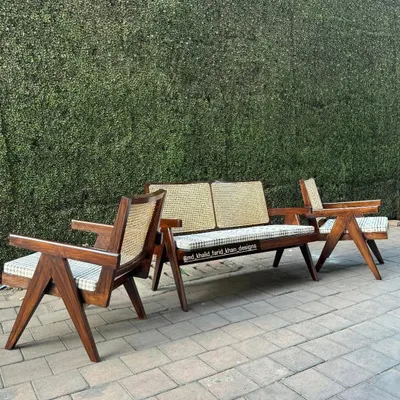 A complete lounge set inspired by the iconic designs of Pierre Jeanneret, featuring a two-seater bench and single armchairs. These are handcrafted from solid teak with hand-woven cane and checkered cushions.
