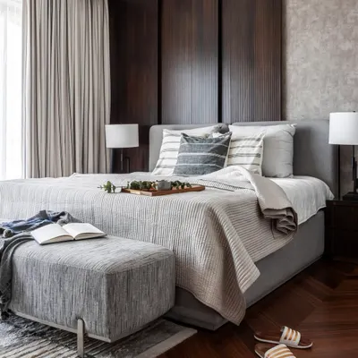 A bedroom designed for slow mornings and quiet luxury. The warmth of dark wood paneling meets soft, layered textiles, creating a space that feels both cozy and contemporary. Herringbone floors and a cool, neutral palette bring a sense of balance.