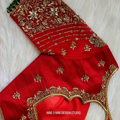 A masterpiece for our bride Madhuri. This classic red bridal blouse is heavily embroidered with zardosi and stone work, featuring a beautiful heart-shaped cutout on the back. The sleeves are a canvas of intricate floral patterns, making it a truly royal piece.