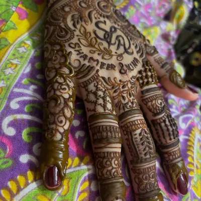 A close up of a personalized bridal henna for Alina, featuring the couple's initials 'S & A' and their names, Shameer and Alina, written below.
