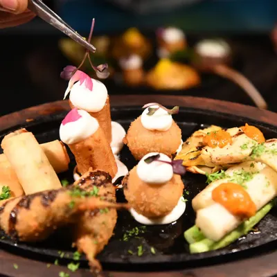 A sizzling platter of assorted tapas, featuring croquettes, spring rolls, and other small bites. This is a great way to sample a variety of flavours.