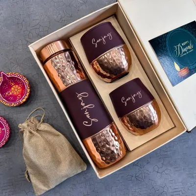 A luxurious Diwali gift set featuring a personalized hammered copper bottle and matching copper glasses. This elegant set comes in a premium box with a Diwali card and diyas.