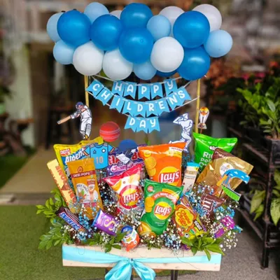 This large Children's Day hamper is packed with fun and flavor. It features a variety of chips, chocolates, and snacks, all topped with a festive balloon arrangement and cricket-themed cutouts, making it a perfect surprise for the little ones.