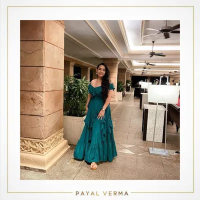 A client enjoying her vacation in a custom-made teal green crepe gown. The off-shoulder design and ruffled layers create a beautiful, flowy silhouette that's perfect for a beachside dinner or resort evening.