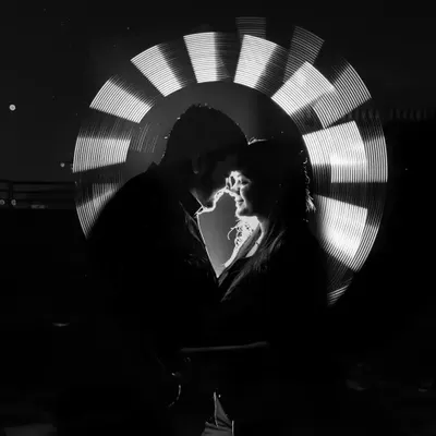 A stunning black and white light painting portrait. By removing the color, we emphasize the silhouette, the light, and the intimate connection between the couple, creating a powerful and artistic image.