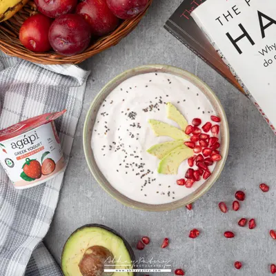 A healthy yogurt bowl styled as part of a wholesome lifestyle. The inclusion of a book and fresh fruits creates a scene of calm, healthy living.