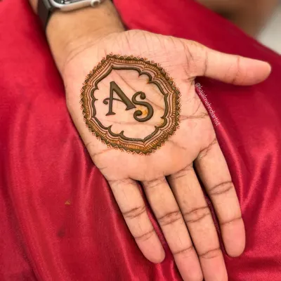 Simple, clean, and elegant henna for the groom. This design features the couple's initials, 'AS', in a stylish font, enclosed within a decorative circular frame.