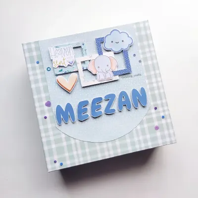 A personalized baby boy scrapbook cover, featuring his name "Meezan" and cute elephant and cloud details. This album comes in a matching gift box.
