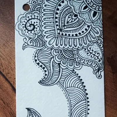 The top half of a hand-drawn bookmark featuring intricate, henna-inspired zentangle patterns made with black pen on paper.