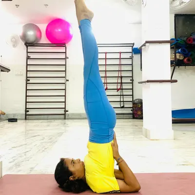 A student holds a perfect Sarvangasana (Shoulder Stand), a pose that improves circulation and calms the nervous system.