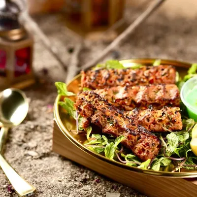 My Mutton Adana Kebabs, perfectly grilled and served on a bed of fresh mint leaves with a side of tangy green chutney. The smoky char and juicy texture make these a real treat.