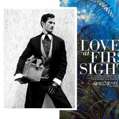 A black and white editorial shot featuring a sharply tailored three-piece suit with a polka-dot tie. The styling, complete with a vintage doctor's bag and skeleton-printed gloves, creates a narrative of a modern-day gentleman with a mysterious edge.