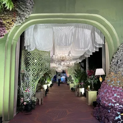 A grand entrance to a magical evening. I designed this arched walkway with massive floral installations and a ceiling of soft, white drapes and chandeliers to create an unforgettable first impression.