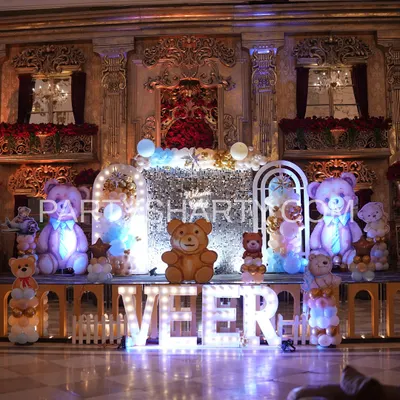 A grand teddy bear stage set against a regal, palace-like wall, featuring large illuminated teddy props and marquee letters for a truly royal feel.