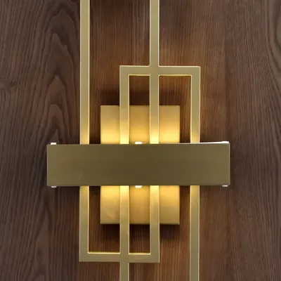We believe luxury is in the details. This custom geometric wall light with a brushed gold finish is not just a source of light but a piece of art, perfectly complementing the rich texture of the wood panel it adorns.