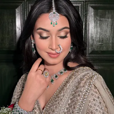 A close-up on the details of this soft glam bridal look. The focus is on the beautifully blended eyeshadow and the flawless base that complements the intricate diamond and emerald jewelry.