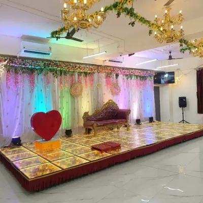 A wide view of our engagement stage setup at the Badlapur hall. It features a royal divan, a large heart prop, and a beautiful floral backdrop, with plenty of space on the LED floor for rituals and photos.