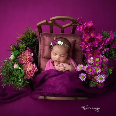 A floral fantasy in shades of purple and pink. This setup features a baby sleeping peacefully in a tiny, ornate bed, surrounded by lush flowers for a rich, artistic portrait.