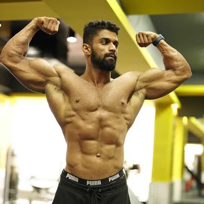 A classic front double biceps pose, showcasing arm development, chest fullness, and a tightly defined midsection. This is a foundational pose in competitive bodybuilding.