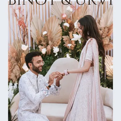The moment it becomes official. Capturing the ring exchange during an engagement ceremony, with a beautifully decorated backdrop adding to the festive atmosphere.