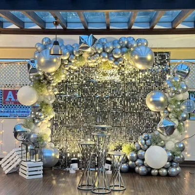 I also create decor for other events, like this glamorous birthday party setup. This design features a full silver shimmer wall backdrop that catches the light beautifully, framed by a silver and white balloon arch with star-shaped foil balloons for extra sparkle.