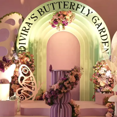 The main stage for a luxurious "Butterfly Garden" party. This enchanting setup uses layered backdrops, custom lettering, and beautiful floral arrangements to create a fairy-tale setting.