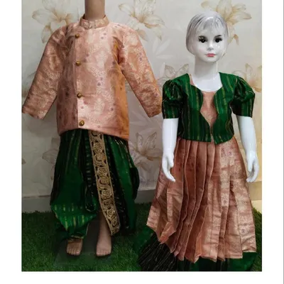 This is a brother and sister ethnic wear set, perfect for festivals or traditional functions. The boy's outfit features a peach Banarasi silk kurta with a green dhoti, complementing the girl's matching Pattu pavadai.