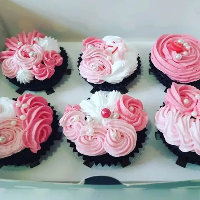 A close look at a box of six chocolate cupcakes, each topped with intricate pink and white vanilla frosting roses and delicate pearl sprinkles. Our BakeStars craft these preservative-free desserts by hand, making them perfect for birthdays or just a little self-love.