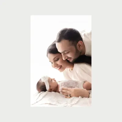 A beautiful color close-up of new parents admiring their sleeping newborn. The soft focus and warm light create an intimate and dreamy portrait, highlighting their love and wonder.