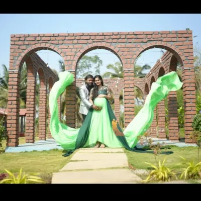 A beautiful couple's maternity portrait featuring our two-tone green flying tail gown. The long, flowing fabric creates a spectacular heart shape, perfectly framing the parents-to-be against a brick archway.