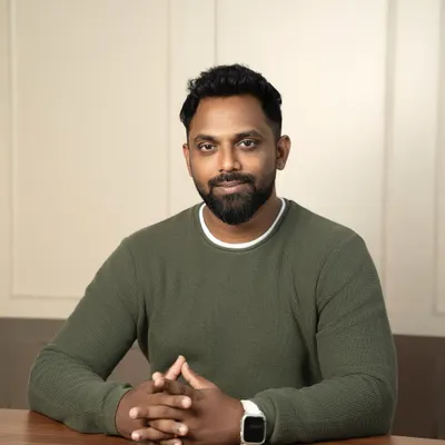 This professional headshot is framed to convey authority and thoughtfulness. The subject is seated at a desk, which adds a corporate context, while the lighting is designed to be flattering yet strong, perfect for an entrepreneur or executive.