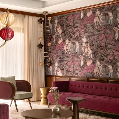 A living room where curated maximalism comes to life. A deep magenta sofa and a statement wallpaper depicting a historical scene create a rich, narrative-driven backdrop, complemented by unique, sculptural lighting fixtures.