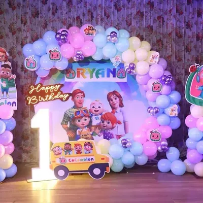 A complete Cocomelon theme for a first birthday party. This setup features a balloon arch in pastel colors, a custom backdrop with the whole Cocomelon family, and character standees.