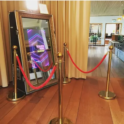 A clean, professional setup of our Mirror Selfie Booth, complete with an interactive "Touch Here to Start" screen. Its elegant, full-length mirror design fits seamlessly into weddings, galas, and corporate functions.