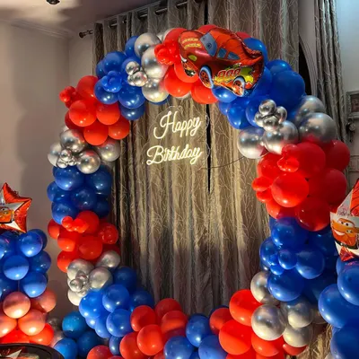 A full circular balloon arch with a 'Cars' theme, perfectly sized to fit in a living room against a curtained wall.