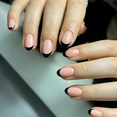 A classic black French manicure on beautifully shaped almond nails. The deep black tip provides a striking contrast against the sheer nude base for a bold, elegant look.