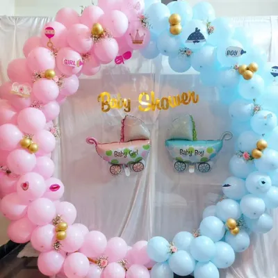 A classic "He or She" baby shower theme, designed with a circular balloon frame in pink and blue. The setup includes "Baby Boy" and "Baby Girl" foil balloons and other small themed details to build excitement for the big reveal.