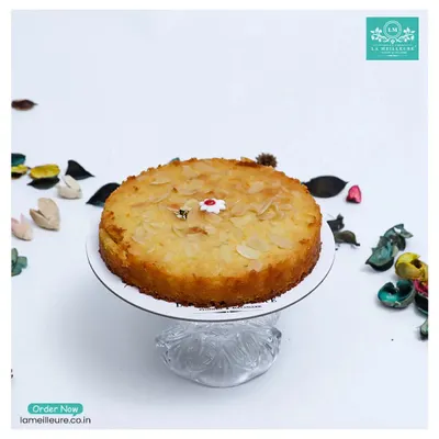 Our Gluten-Free Orange & Almond Tea Cake, presented on a beautiful glass stand. This moist and flavourful cake is a delicious option for everyone to enjoy.